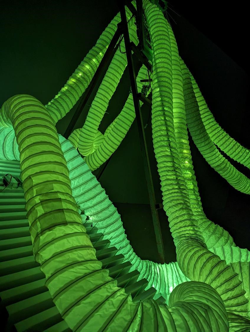 Glowing green tubes stretch through a darkened space.