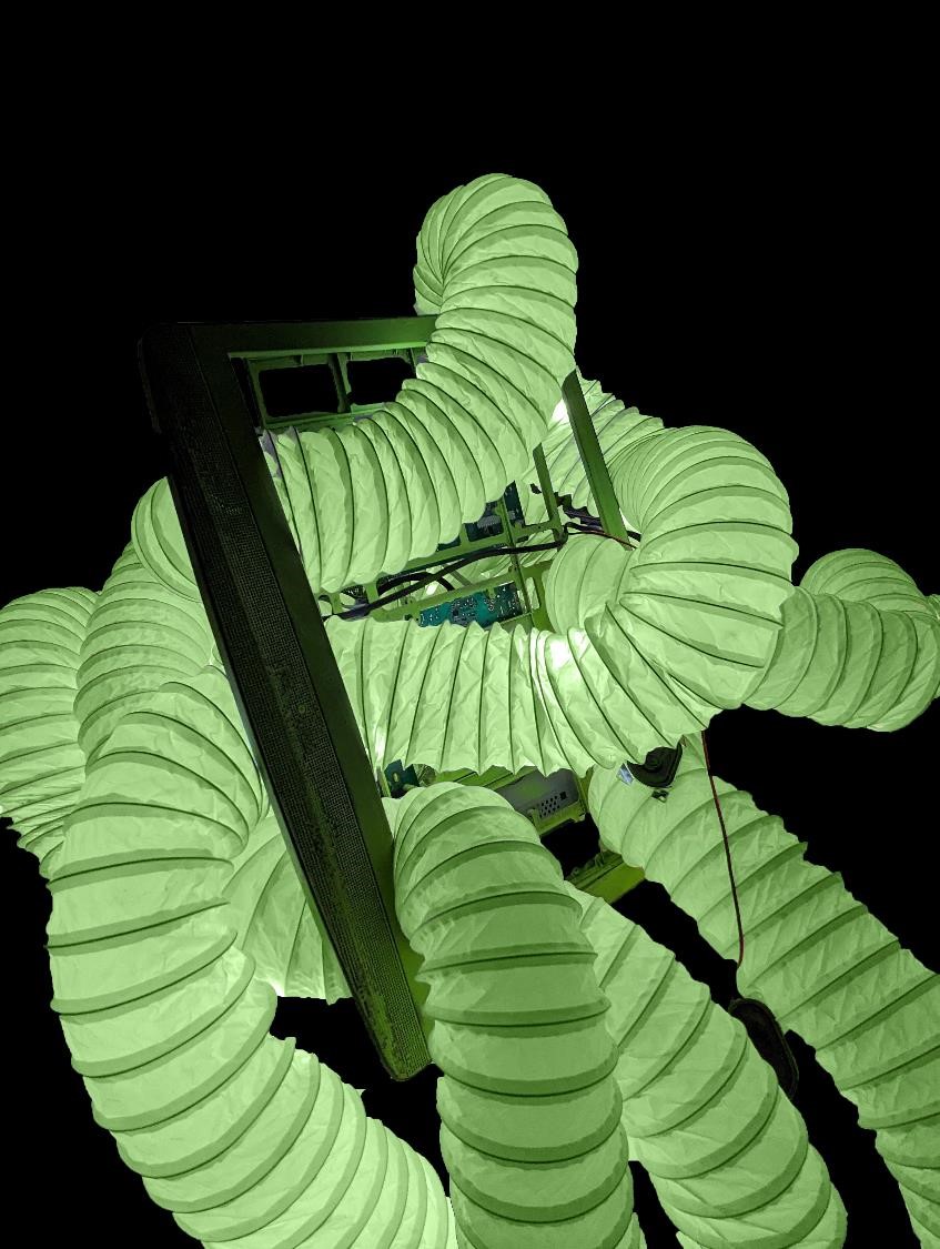 Glowing green ventilation tube burrows in and out of a computer monitor.