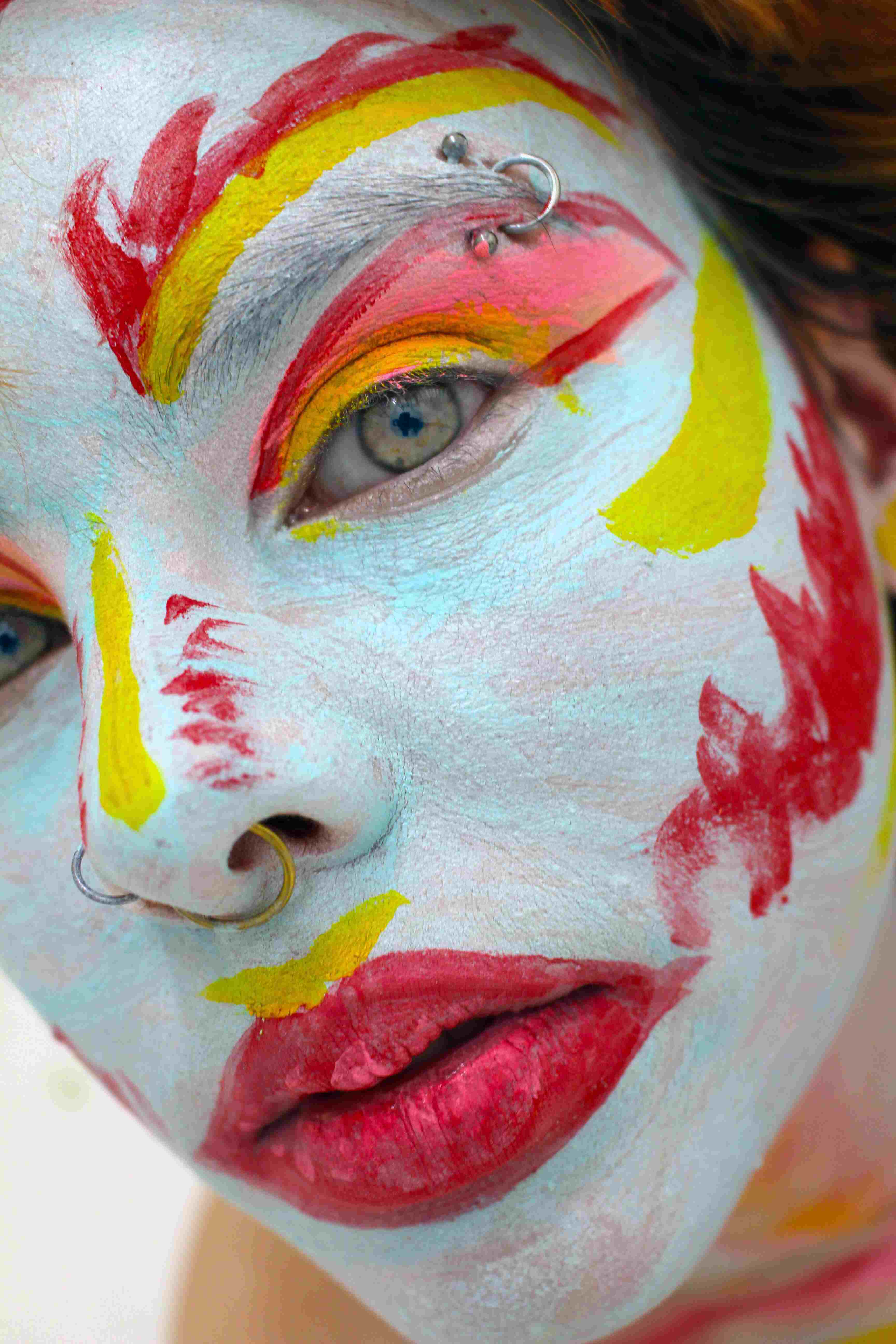 A self-portrait of the artists face painted in exaggerated drag make-up.
