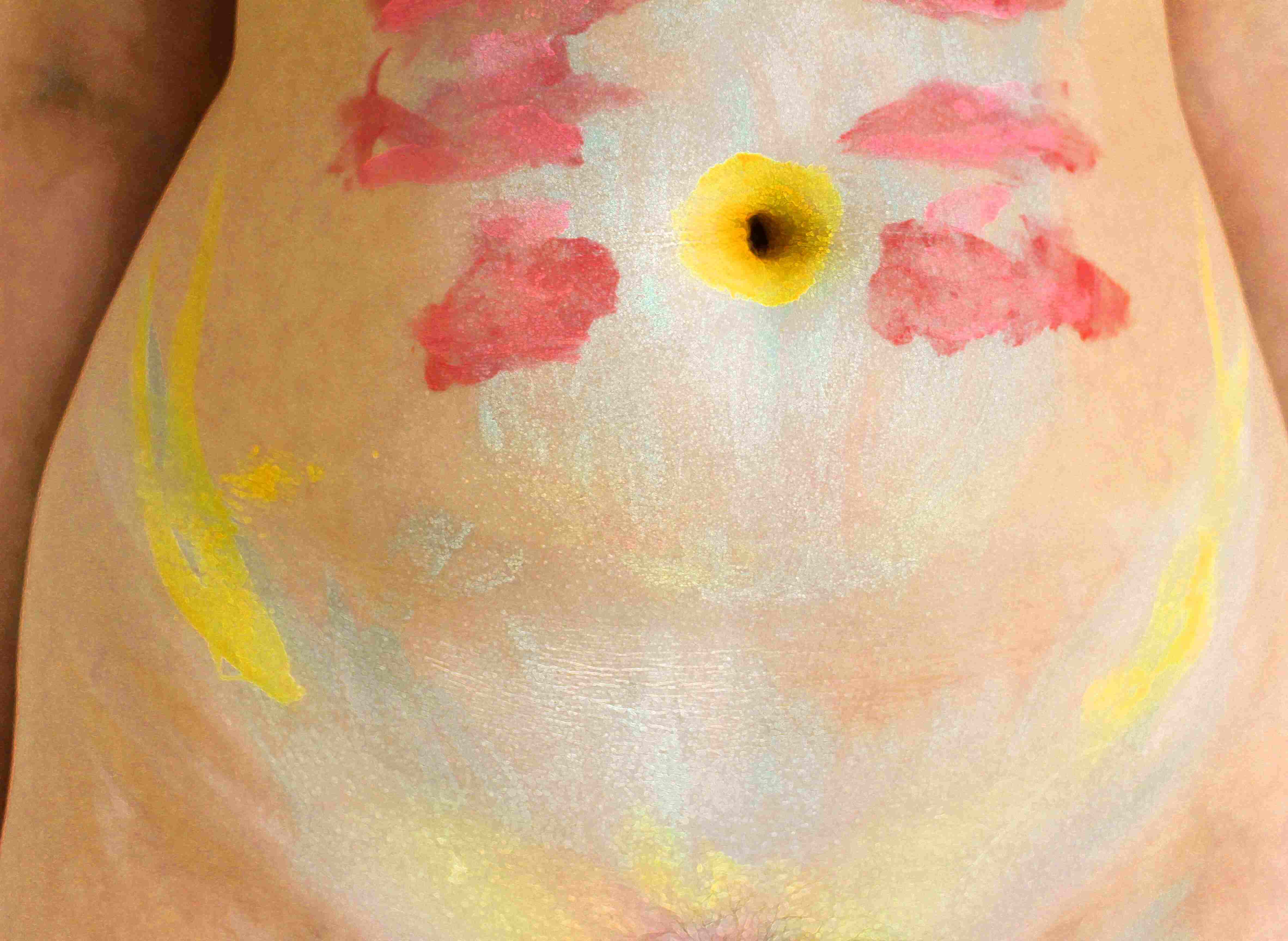 The artists belly photographed up close with facepaint on it.