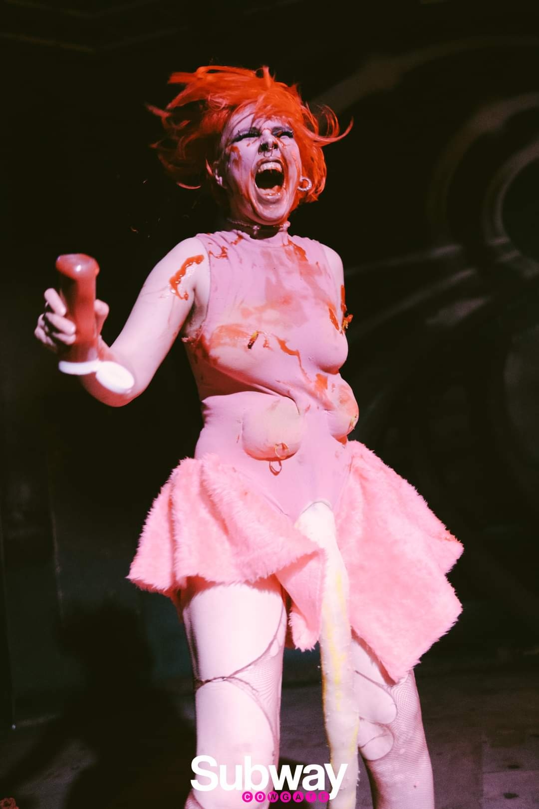 a screaming drag performer, dressed in pink and covered in ketchup