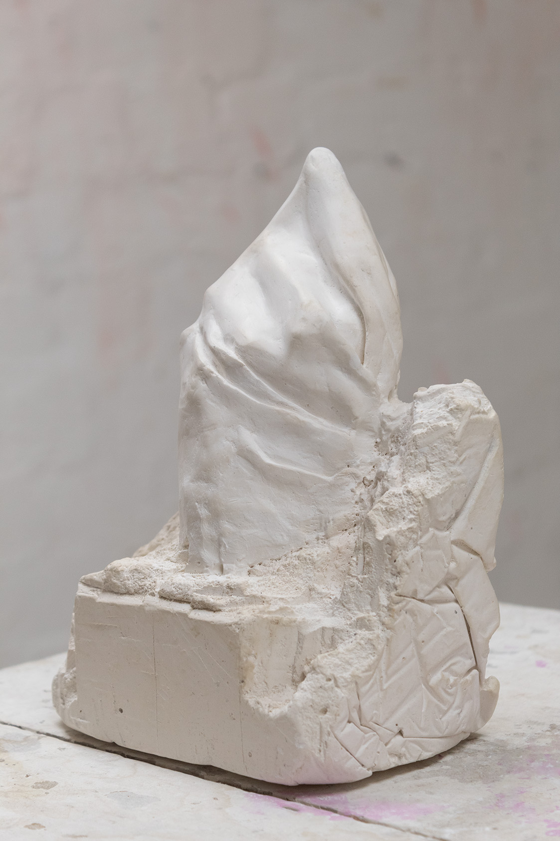 Plaster sculpture of a pointing finger emergaing from a mass of its medium.