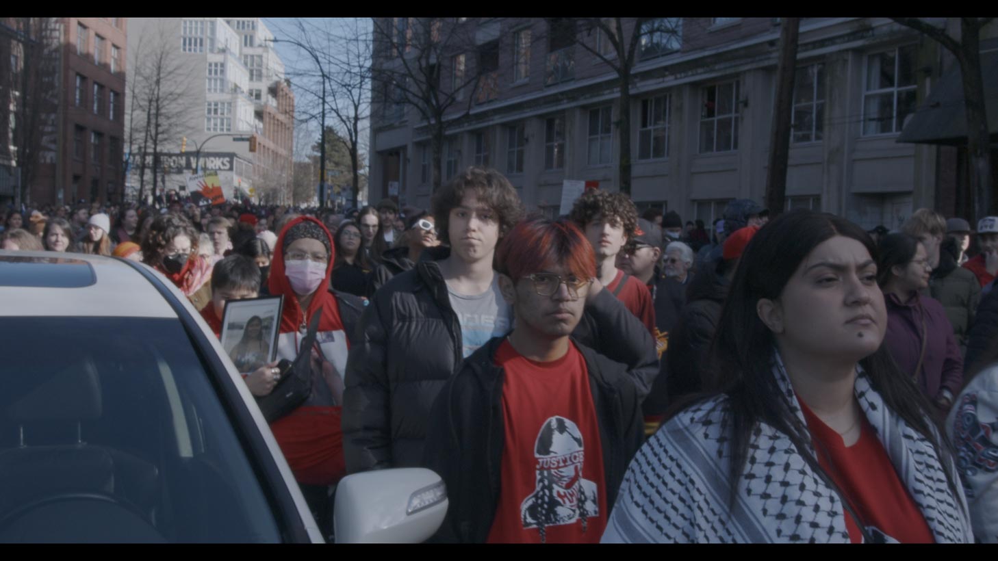 Large crowd of people in red on city street during a march 