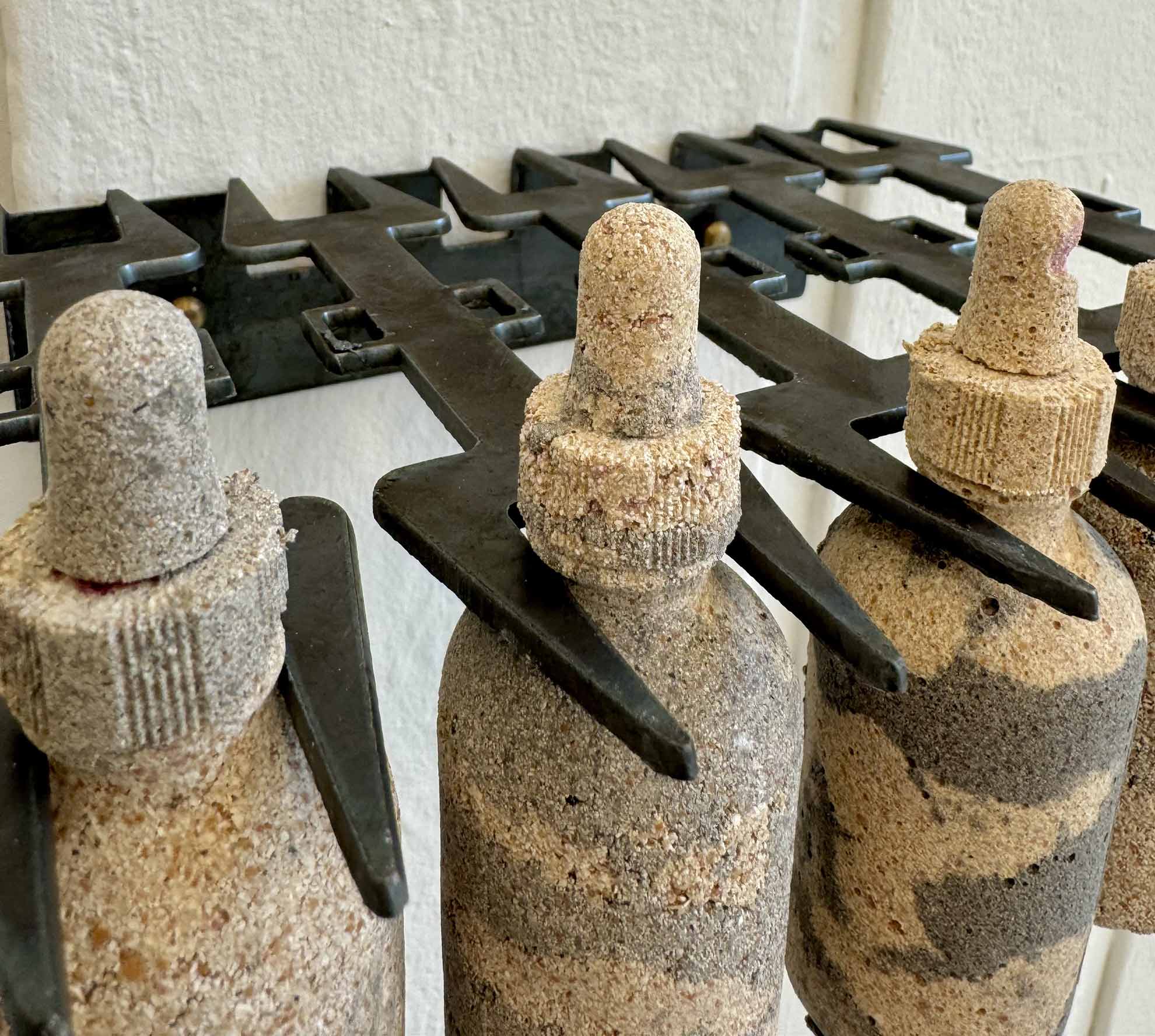 close up of 5 tincture bottles made from egg shell ceramic hung by their necks by a heretic fork style shelving 