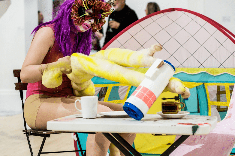 a drag creature picking up a flask with elongated arms