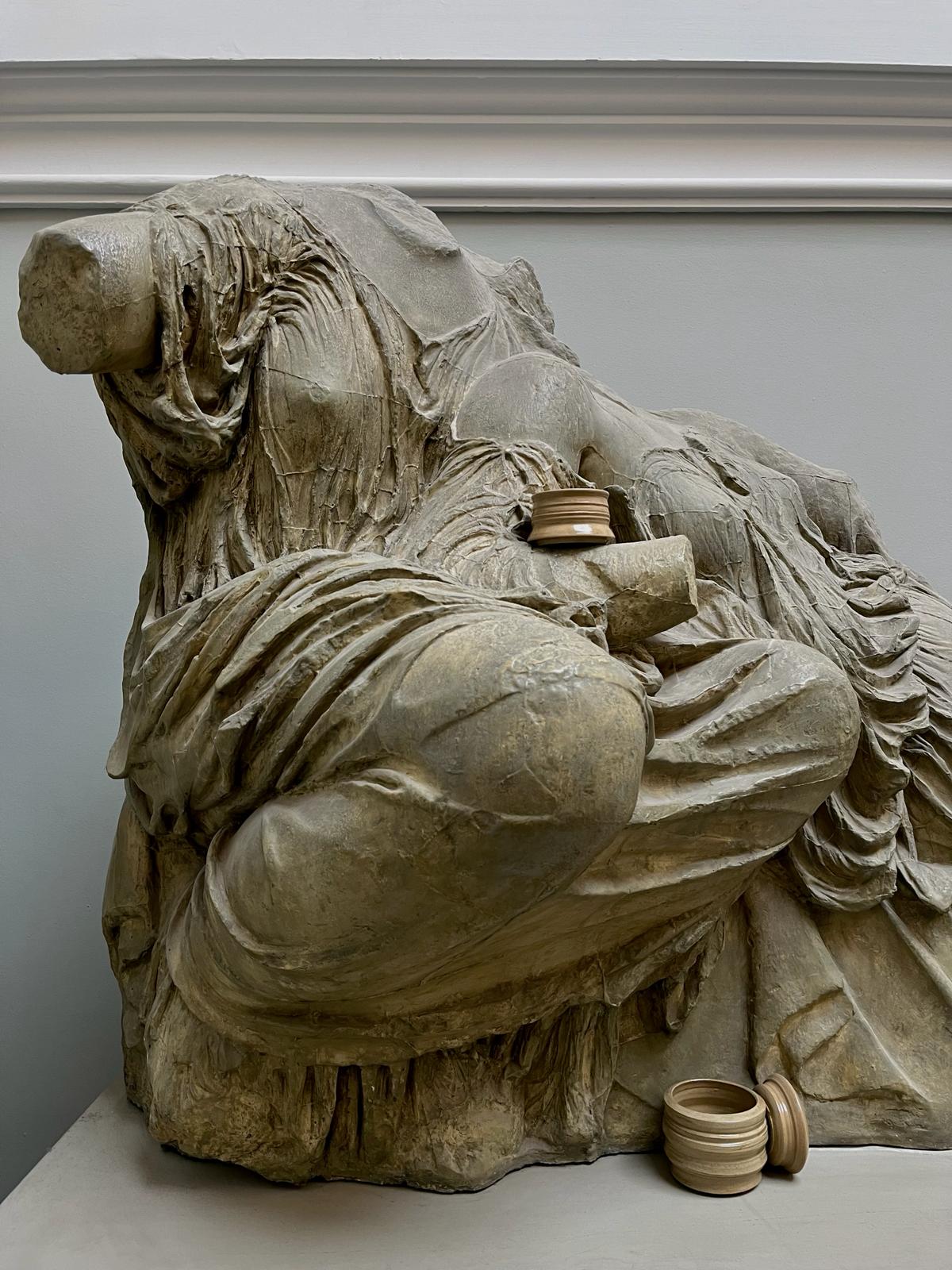 Three ceramic forms placed around a statue.