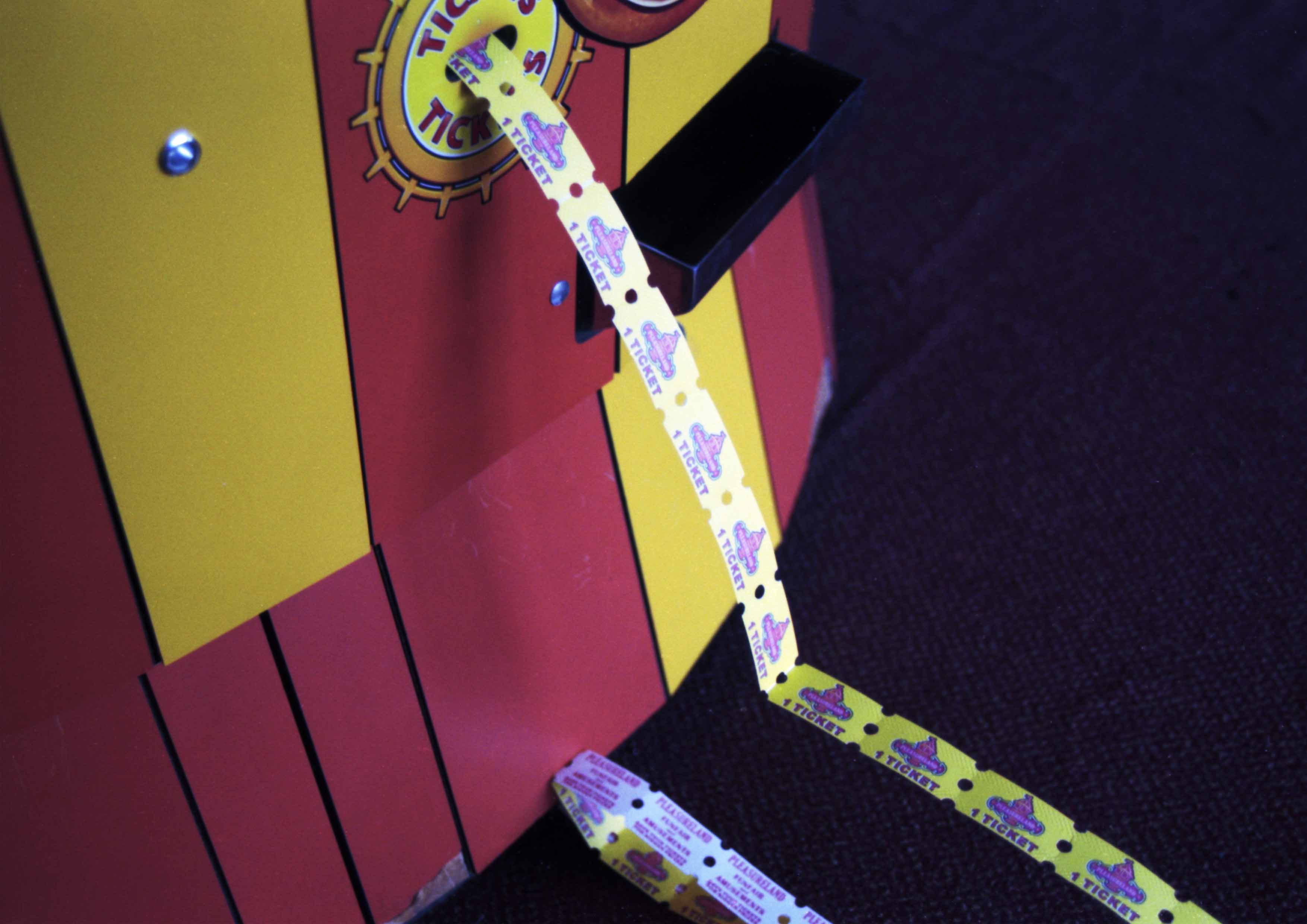 The image captures a red and yellow arcade machine with dispensed tickets on the floor