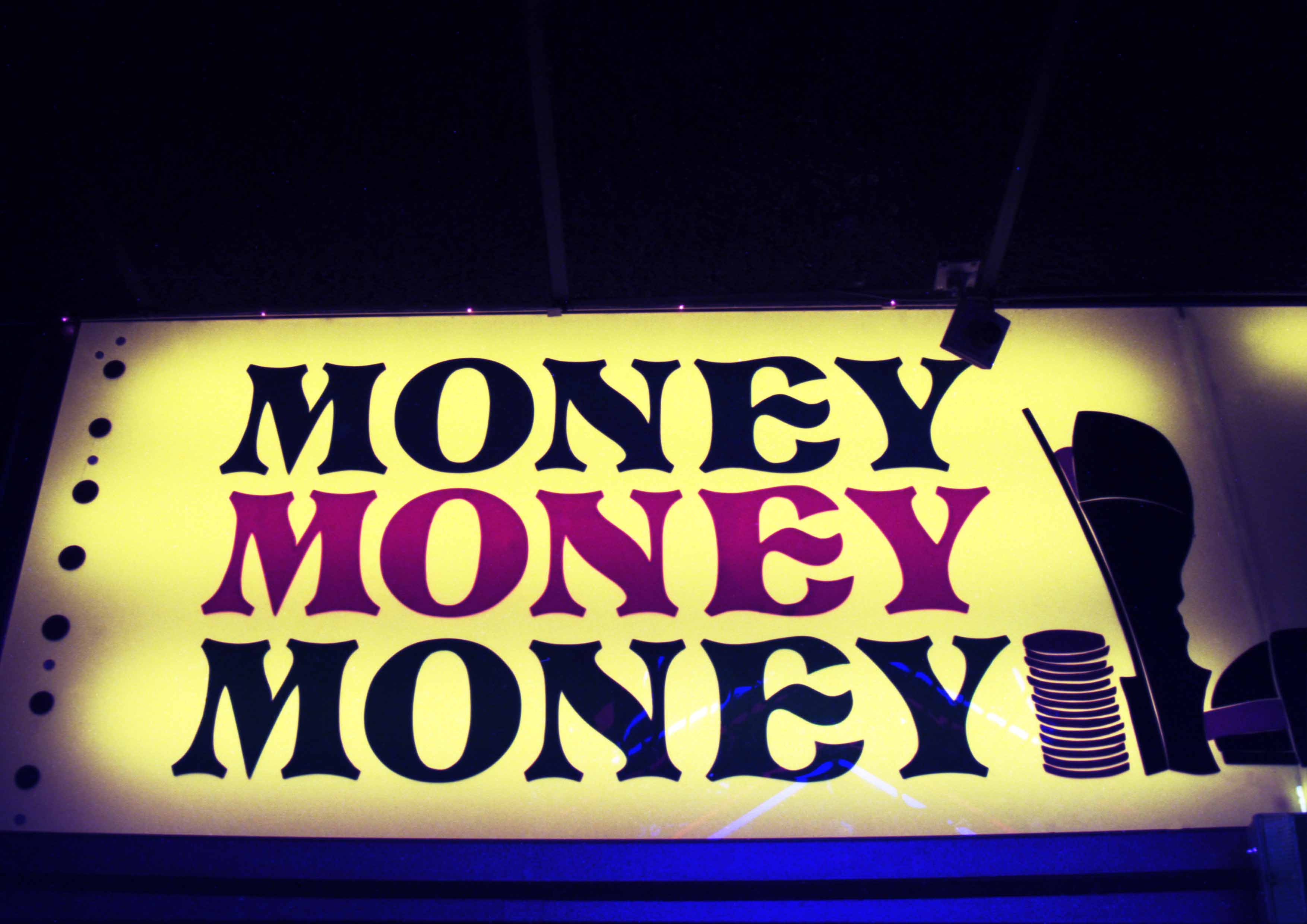 The image captures a large illuminated arcade sign which reads MONEY MONEY MONEY in red and black print