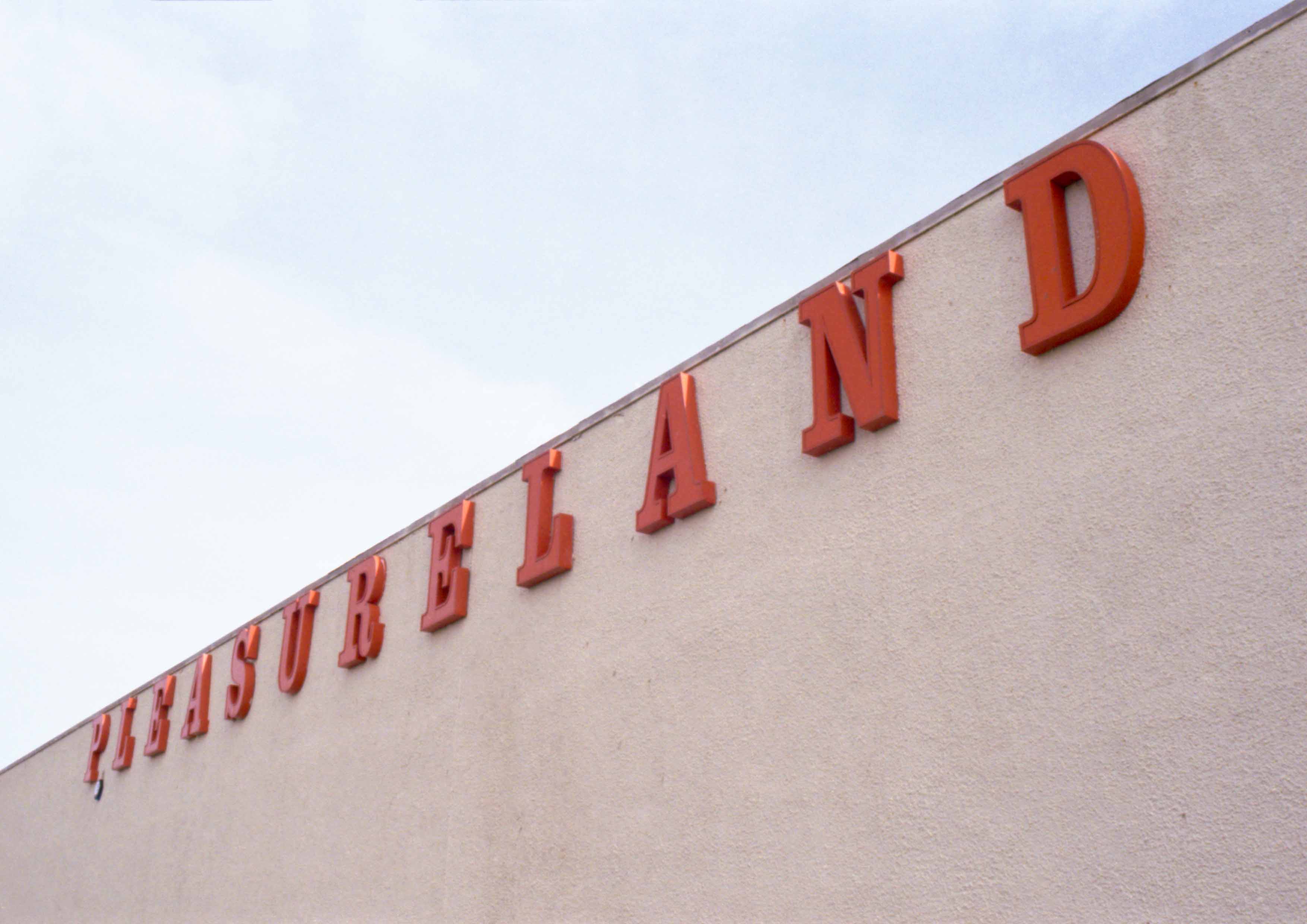 The image captures a building with large orange print which reads PLEASURELAND in large letters. 