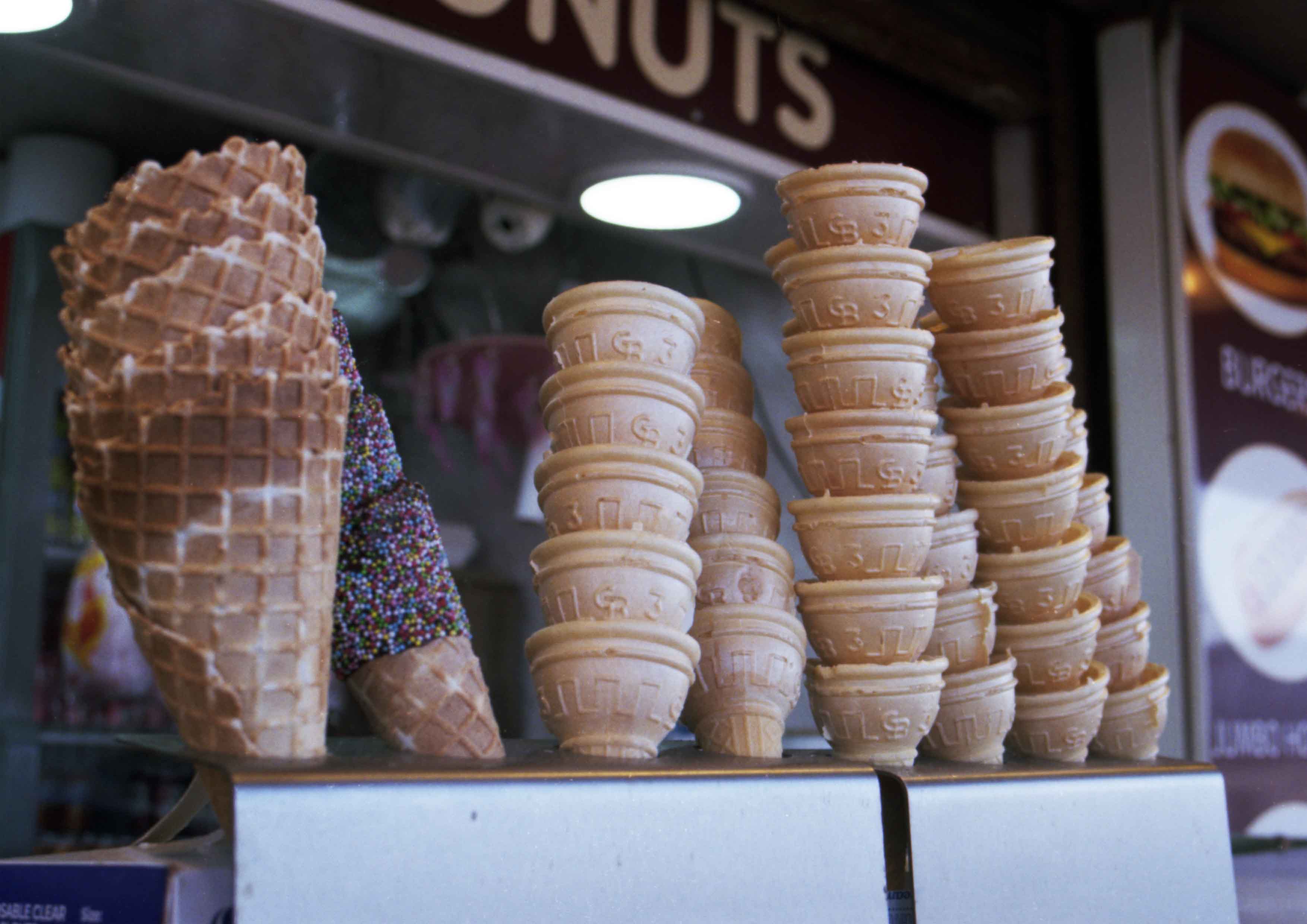 Image captures multiple, repeated ice cream cones stacked on a cafe counter