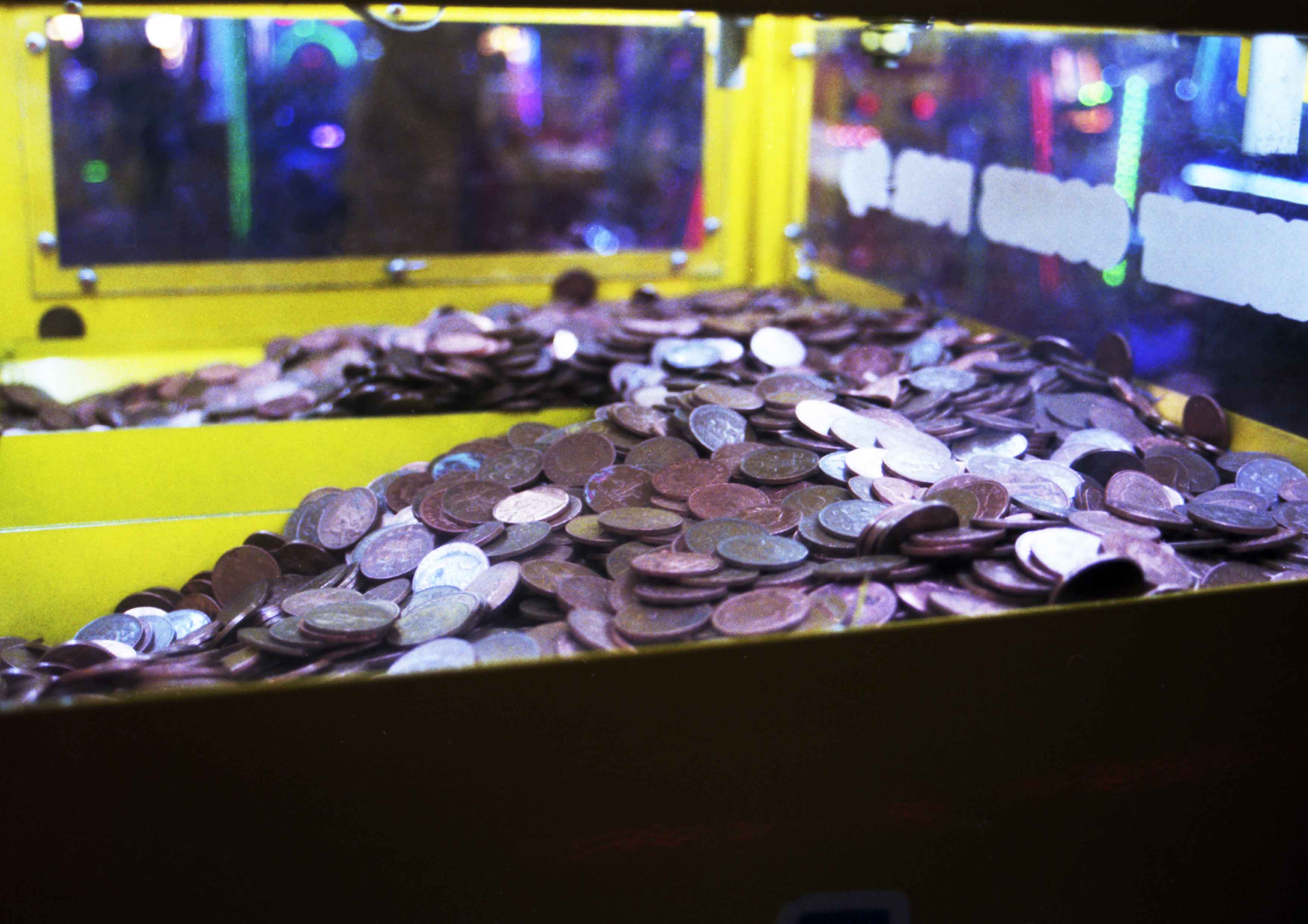 Image captures in interior of a yellow change machine in an arcade. The pennies create reflective surfaces