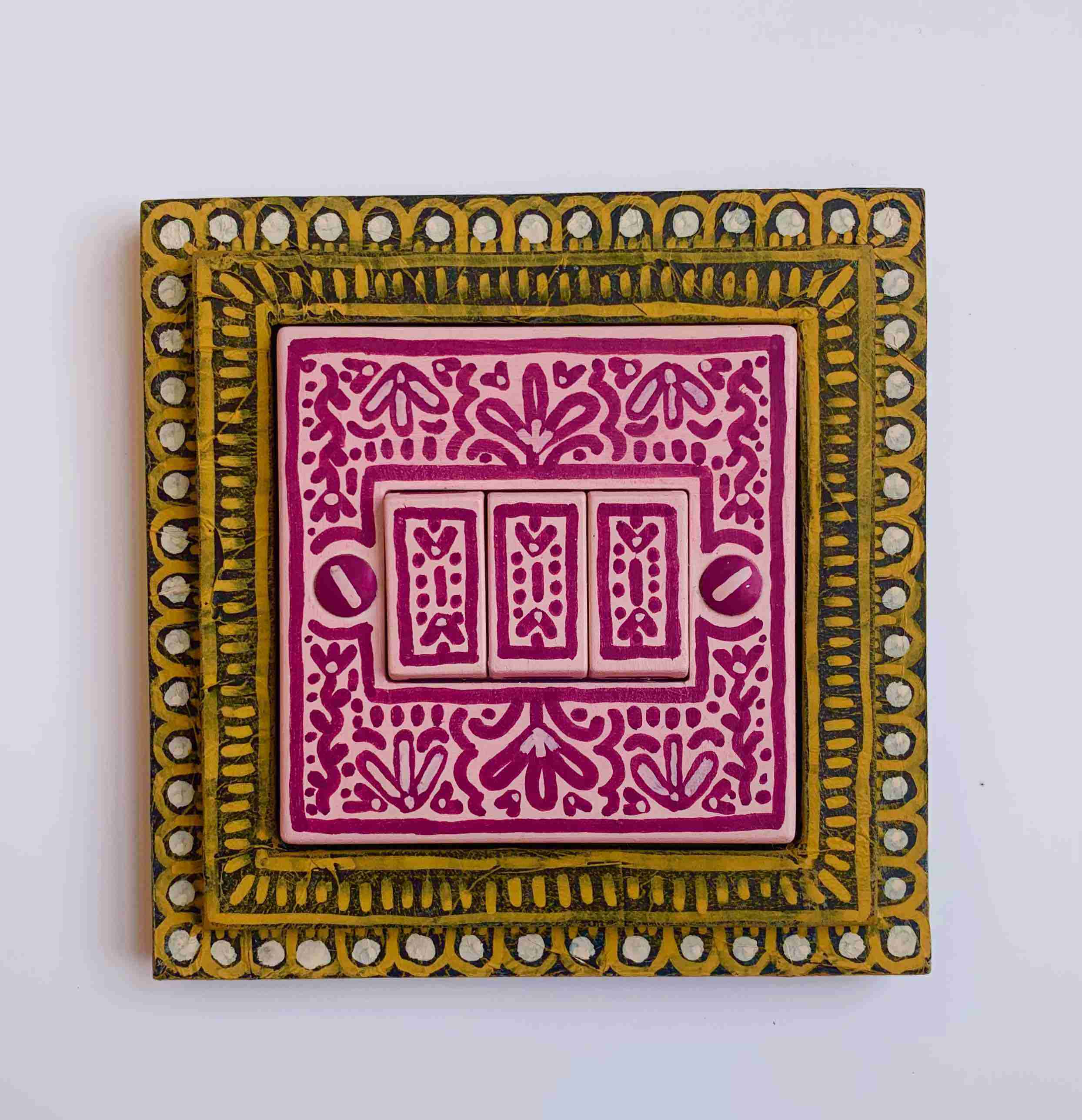 pink painted lightswitch with decorative yellow frame