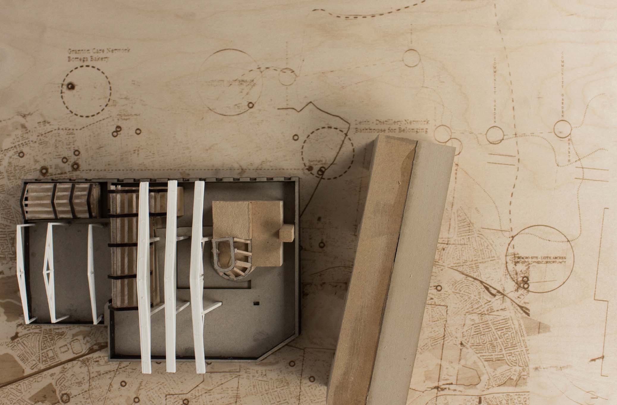 image shows a birds eye view of the proposed bathhouse. Three small interventions (a sauna house, bathhouse and washhouse) sit within an existing building, behind Leith arches. These interventions sit between existing trusses spaced at irregular intervals