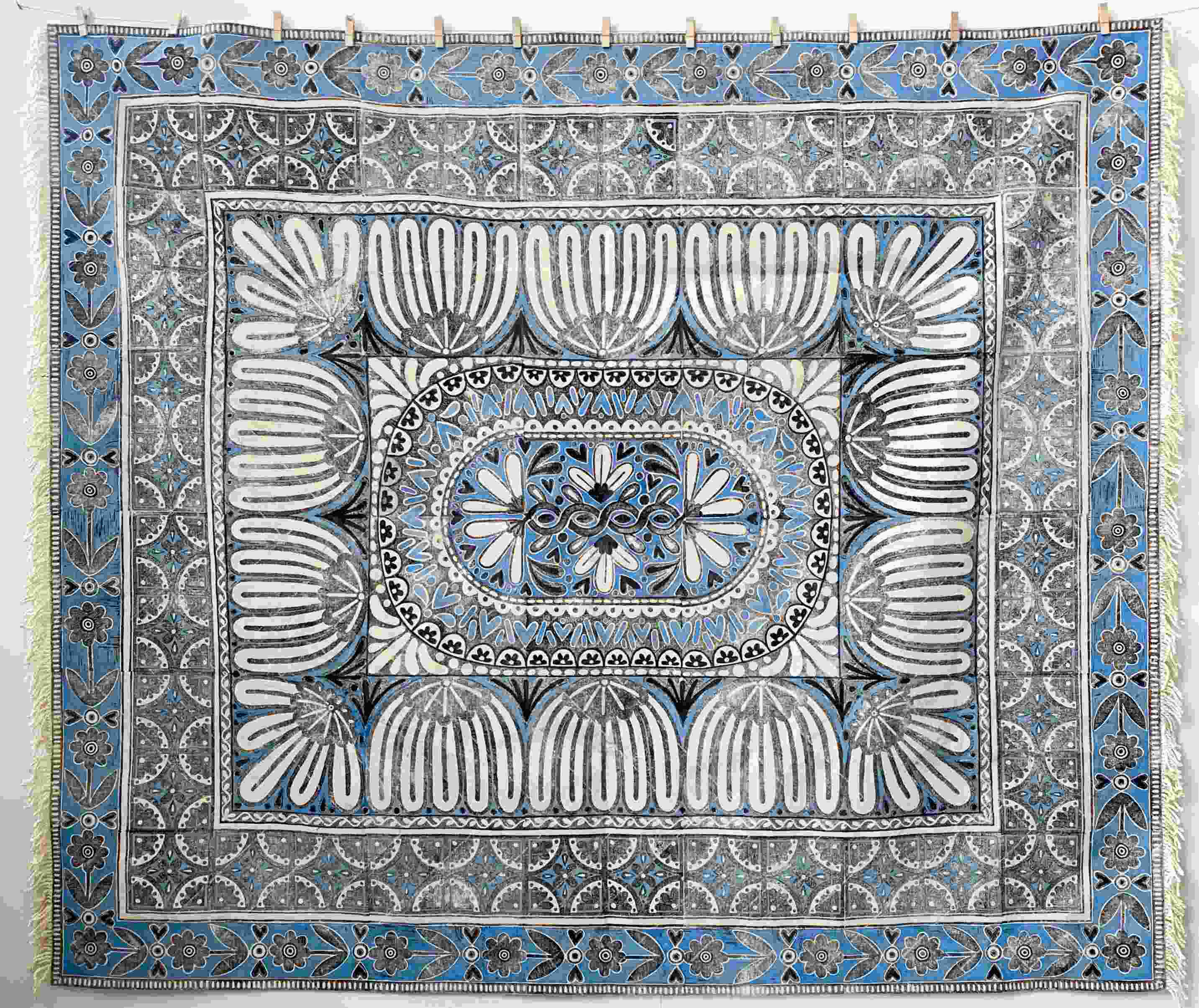 blue, white and black lino printed rug hanging on a wall