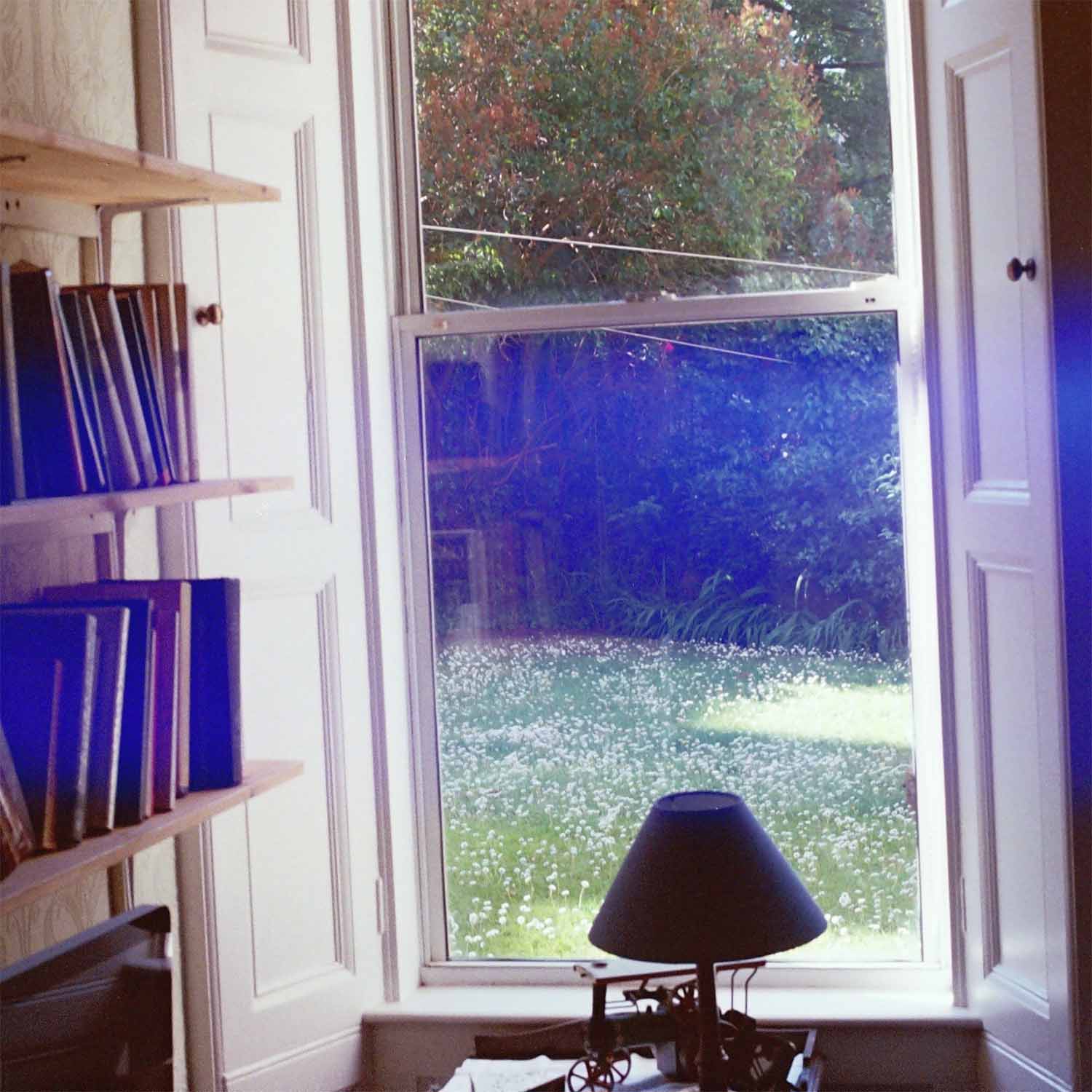 Joe Haynes' 'intricate' EP cover - a lamp sits outside a window, showing a garden with wild flowers and a washing line. The picture is made with film.