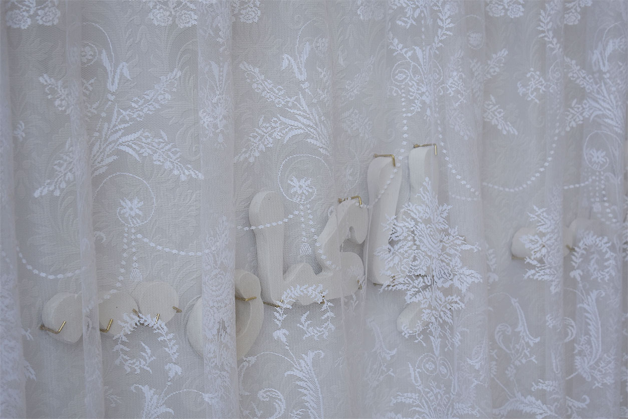 arabic plaster letters mounted behind lace curtain