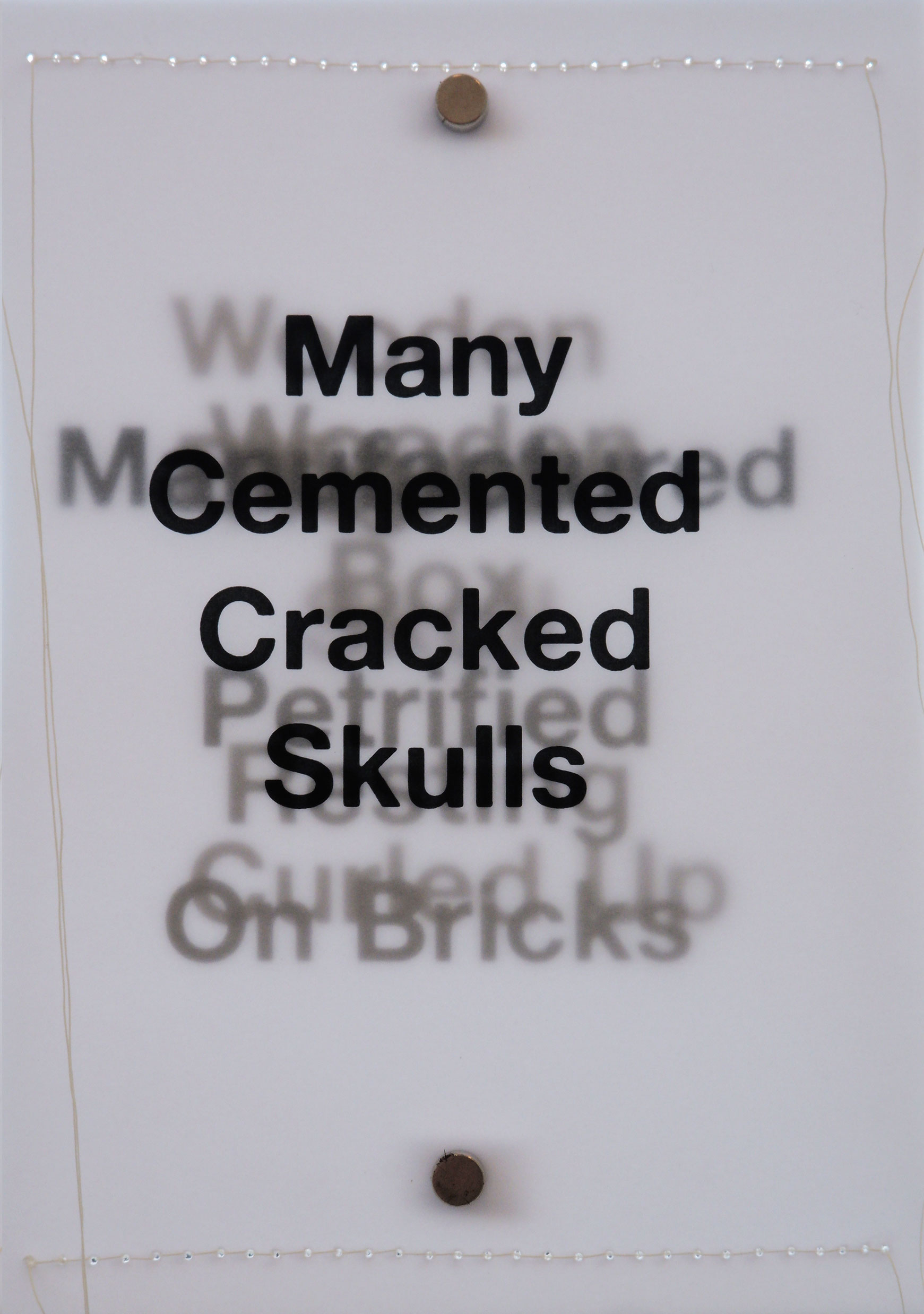 Layers of black text backlit on tracing paper with white stitching along short sides