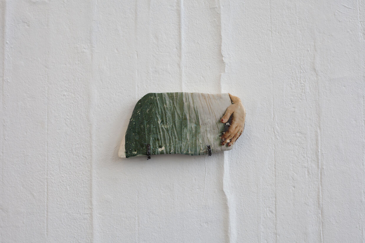 image of hand and fabric on ceramic on a wall 
