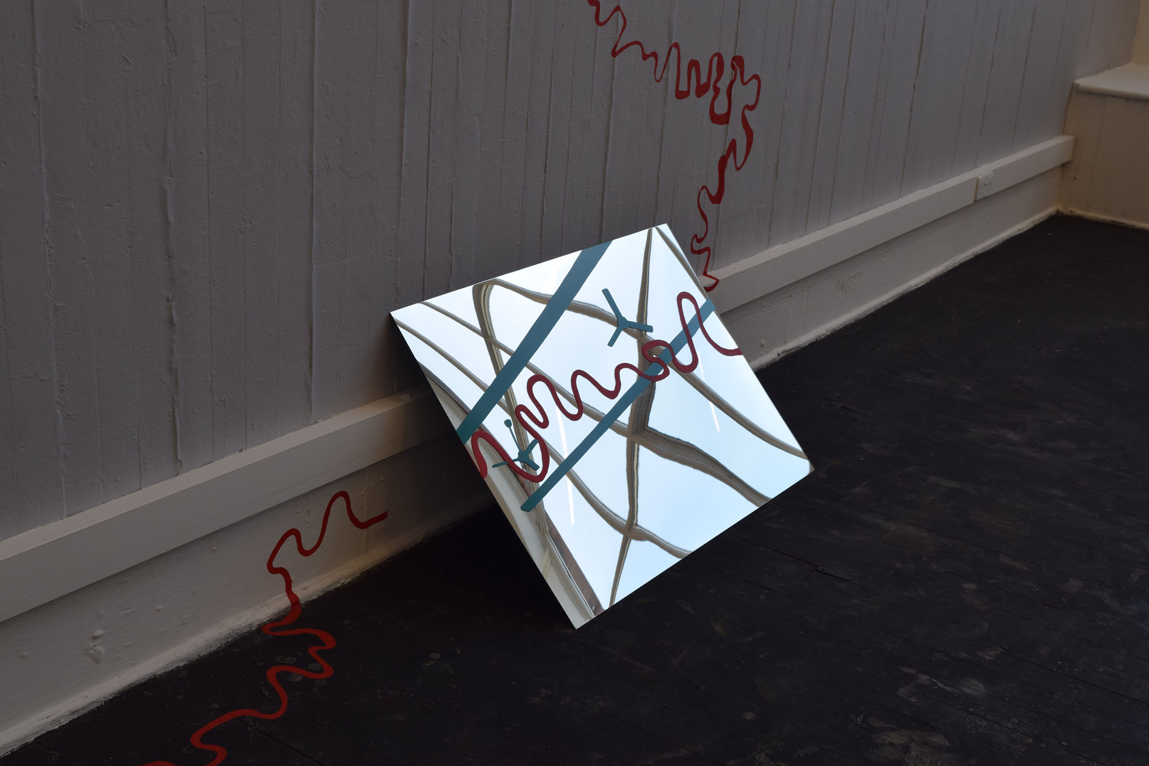 Mirror leaning against a wall with a red line painted over it.