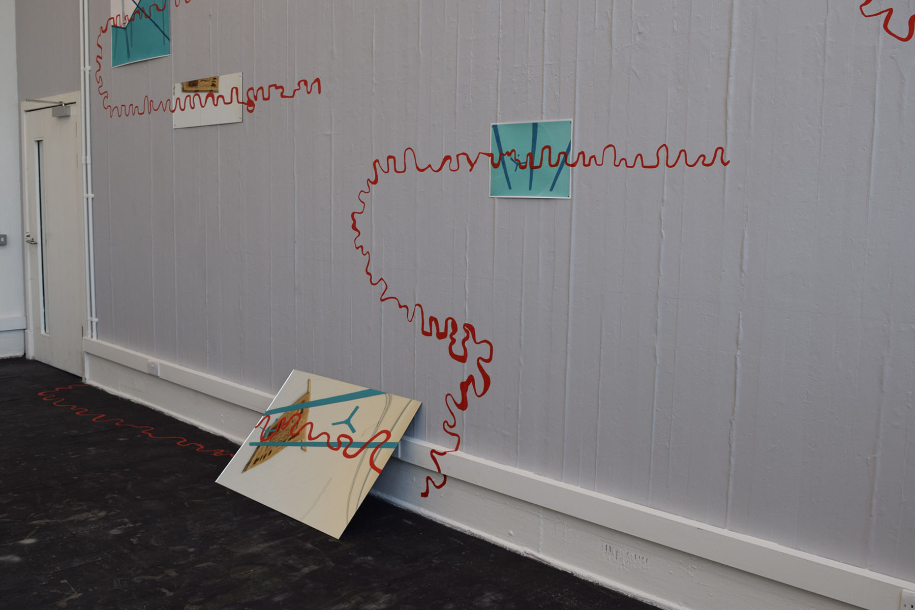 Mirror leaning against a wall with a red line painted over it.