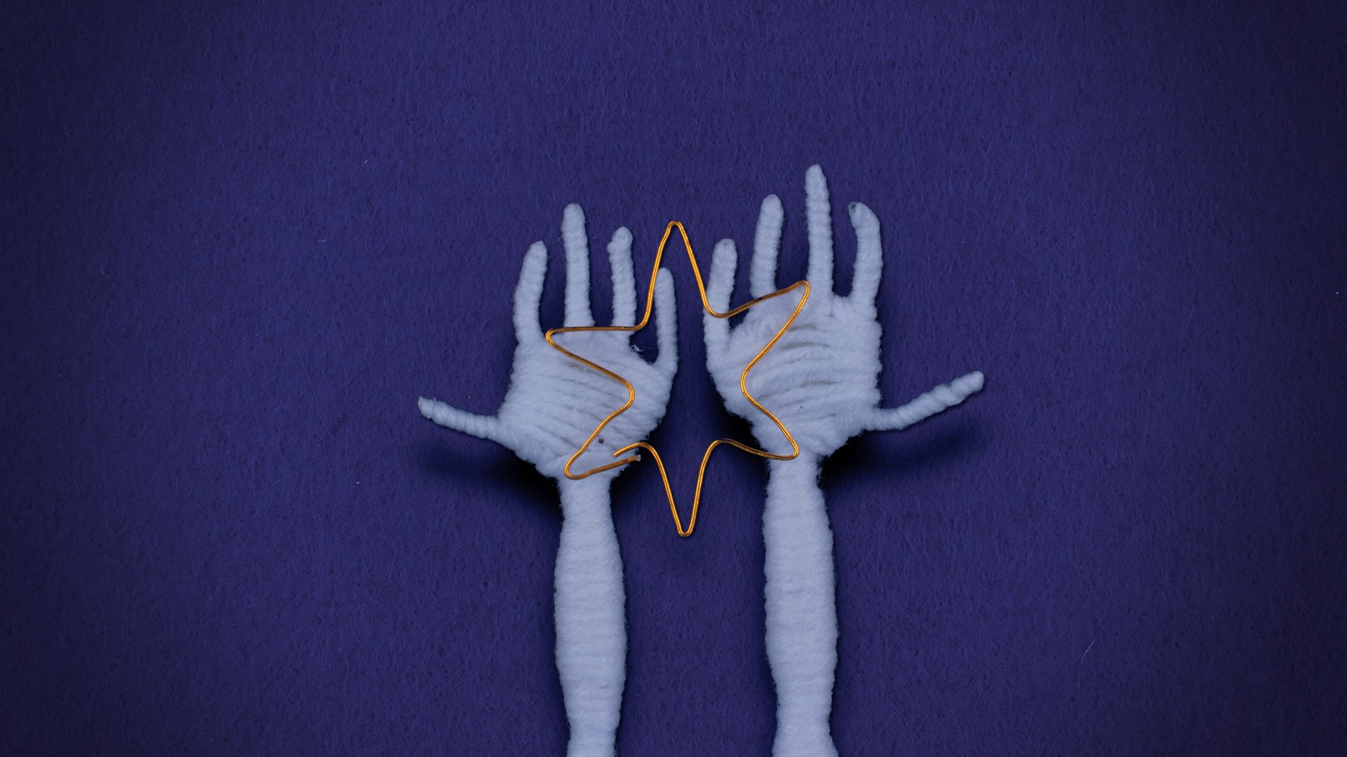 Hands made of yarn hold a golden wire star