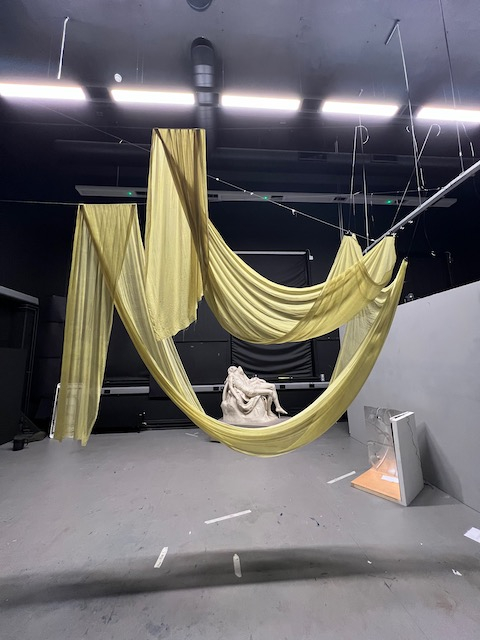 Draped green fabric hanging from the ceiling. Cast of Michelangelo's Pieta in the background