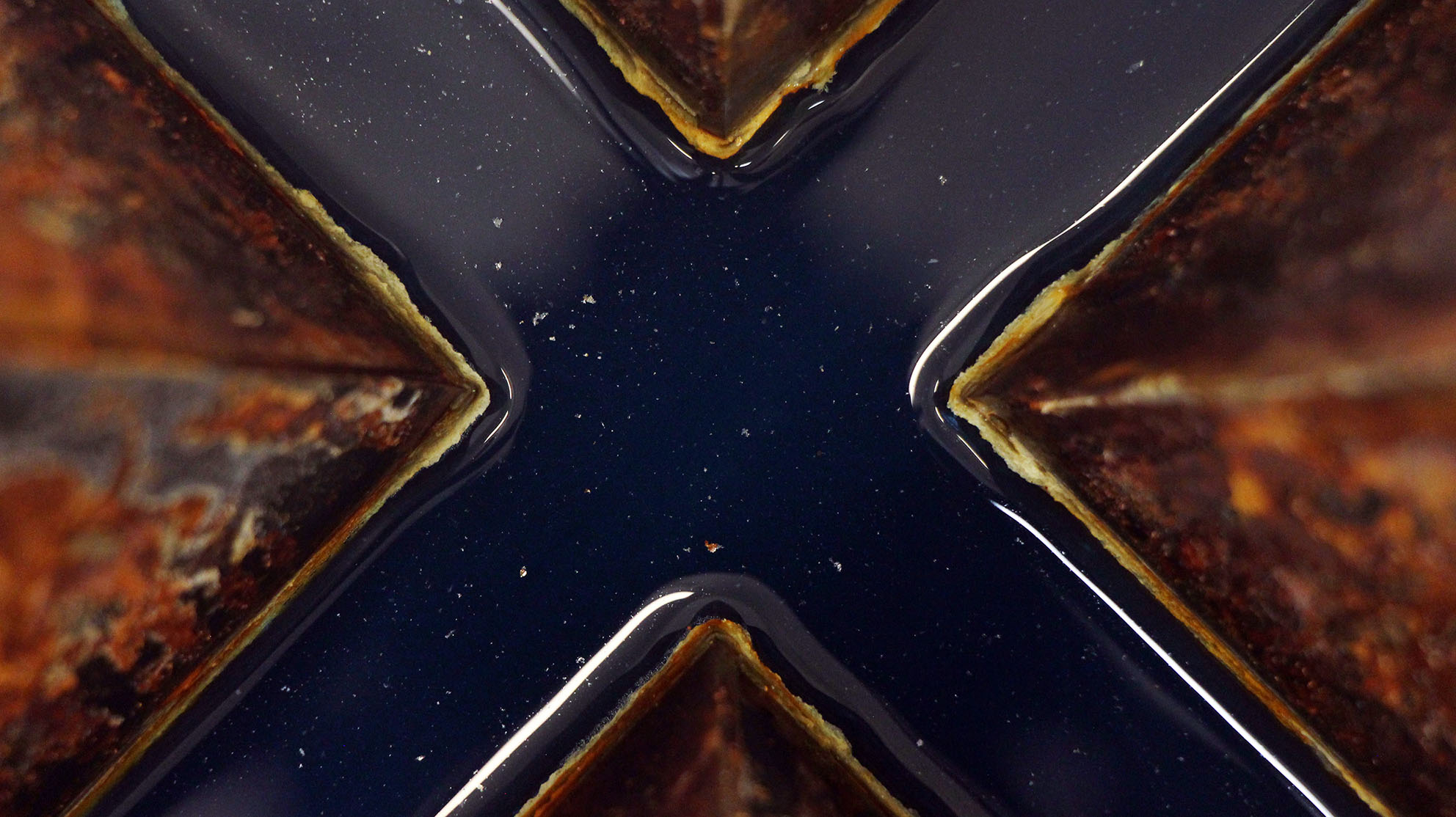 steel rusted sculpture seen close up, showing blue water inside cross