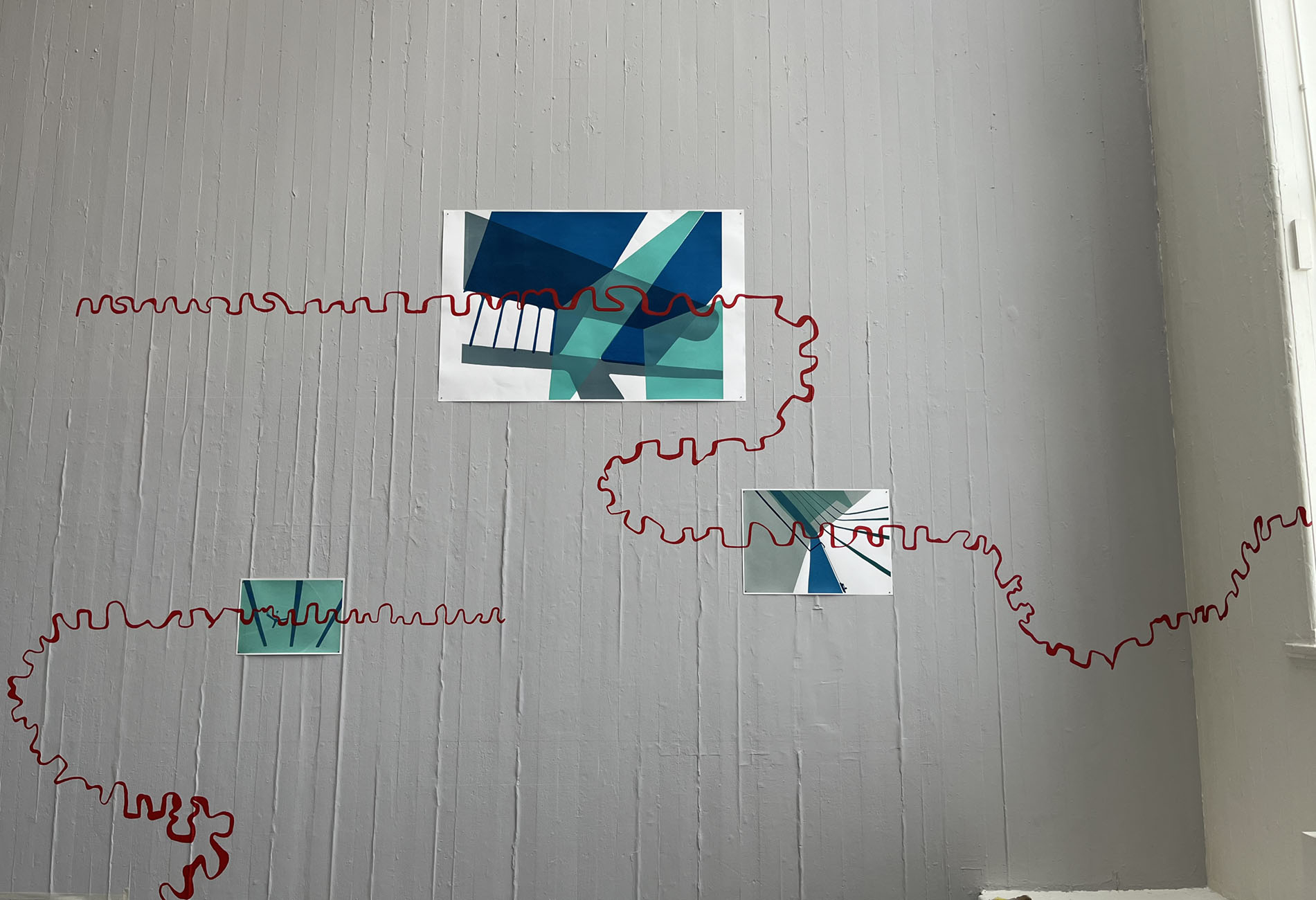 Screen prints with a painted red line running over the print and the wall.