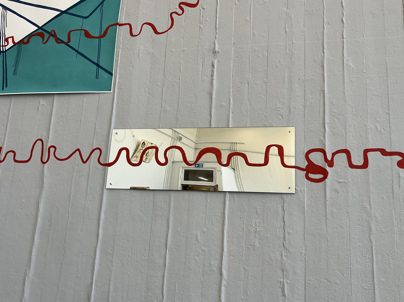 Mirror on a grey wall with a red line painted over it.