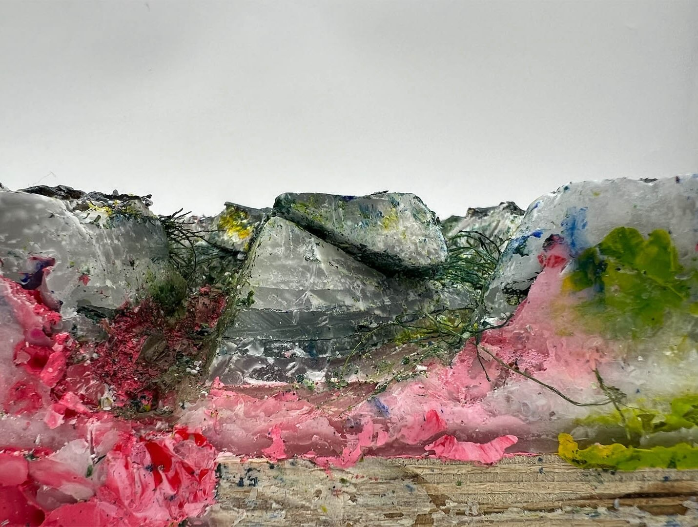 Photo of wax block close up showing layers of wood, different paint colours, and wax.