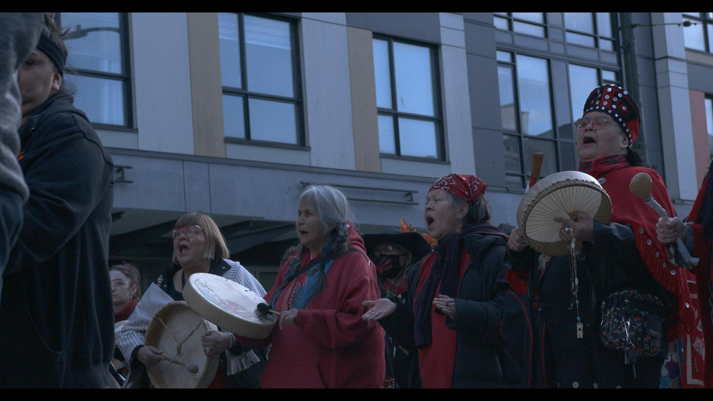 Line of women in red playing drums and chanting at march 