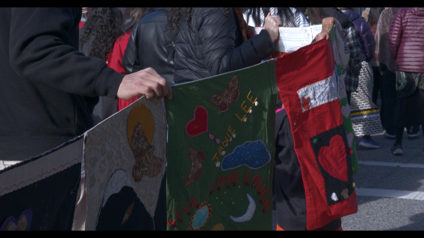 People holding memorial quilts at march 