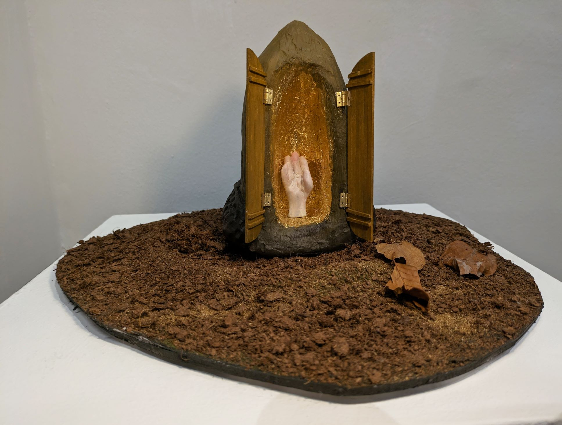 A sculpture of an altar in the shape of an acorn, with a small hand inside