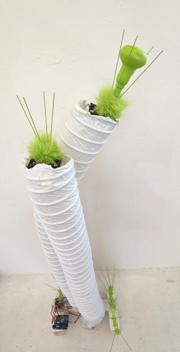 White worm-like tubes wave vertically, with bright green fur and spikes appearing out their ends.