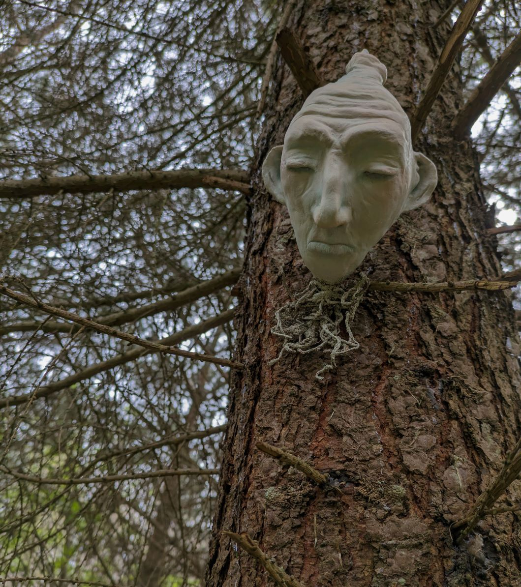 Bulb with a human face mounted on tree.