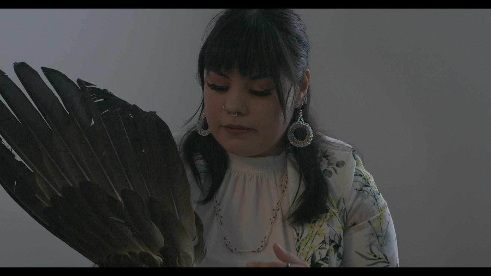 Women in a white room displaying a ceremonial eagles wing 
