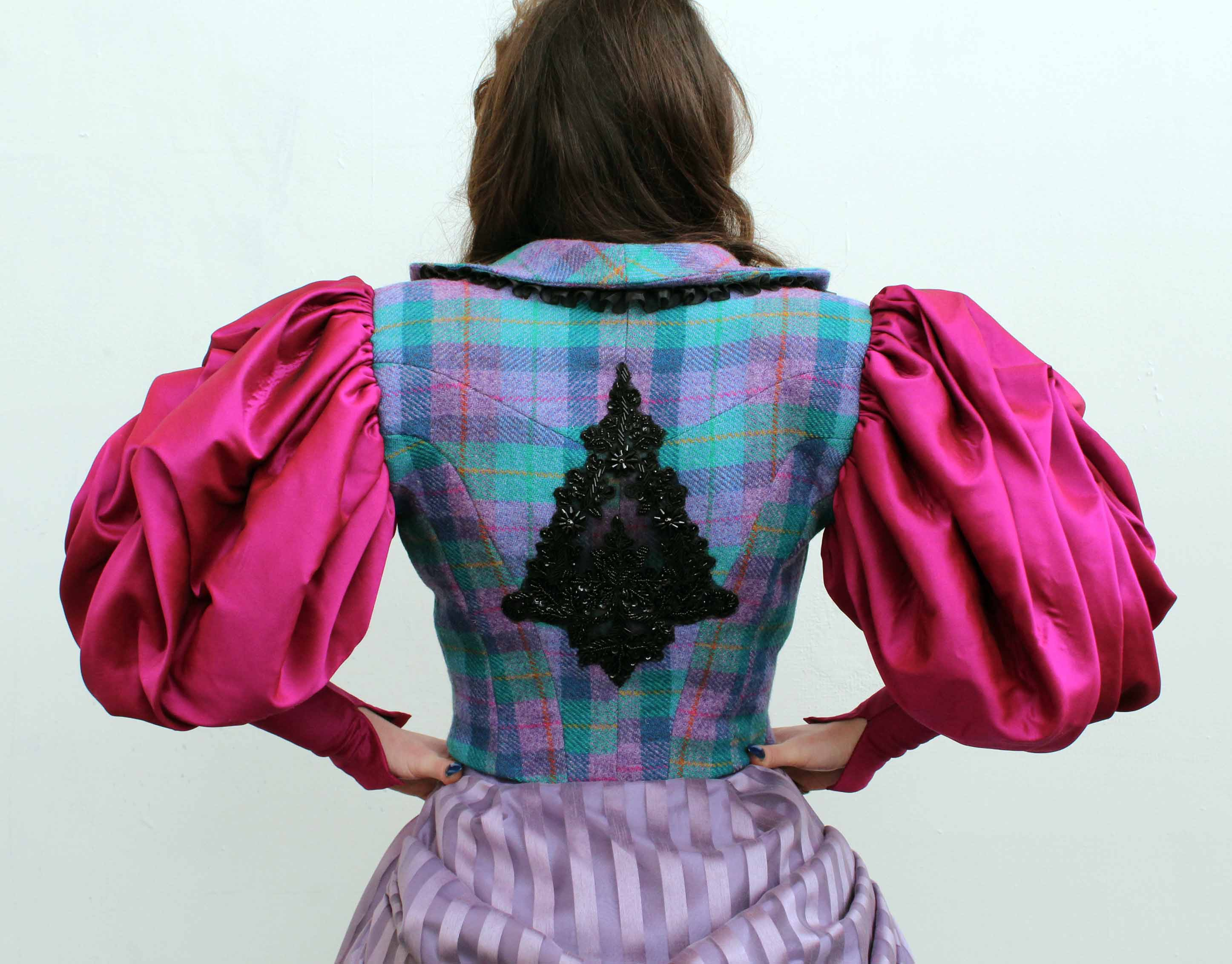 back view of a costume consisting of a checked wool waistcoat and large fuchsia silk sleeves sewn in the shape of roses 