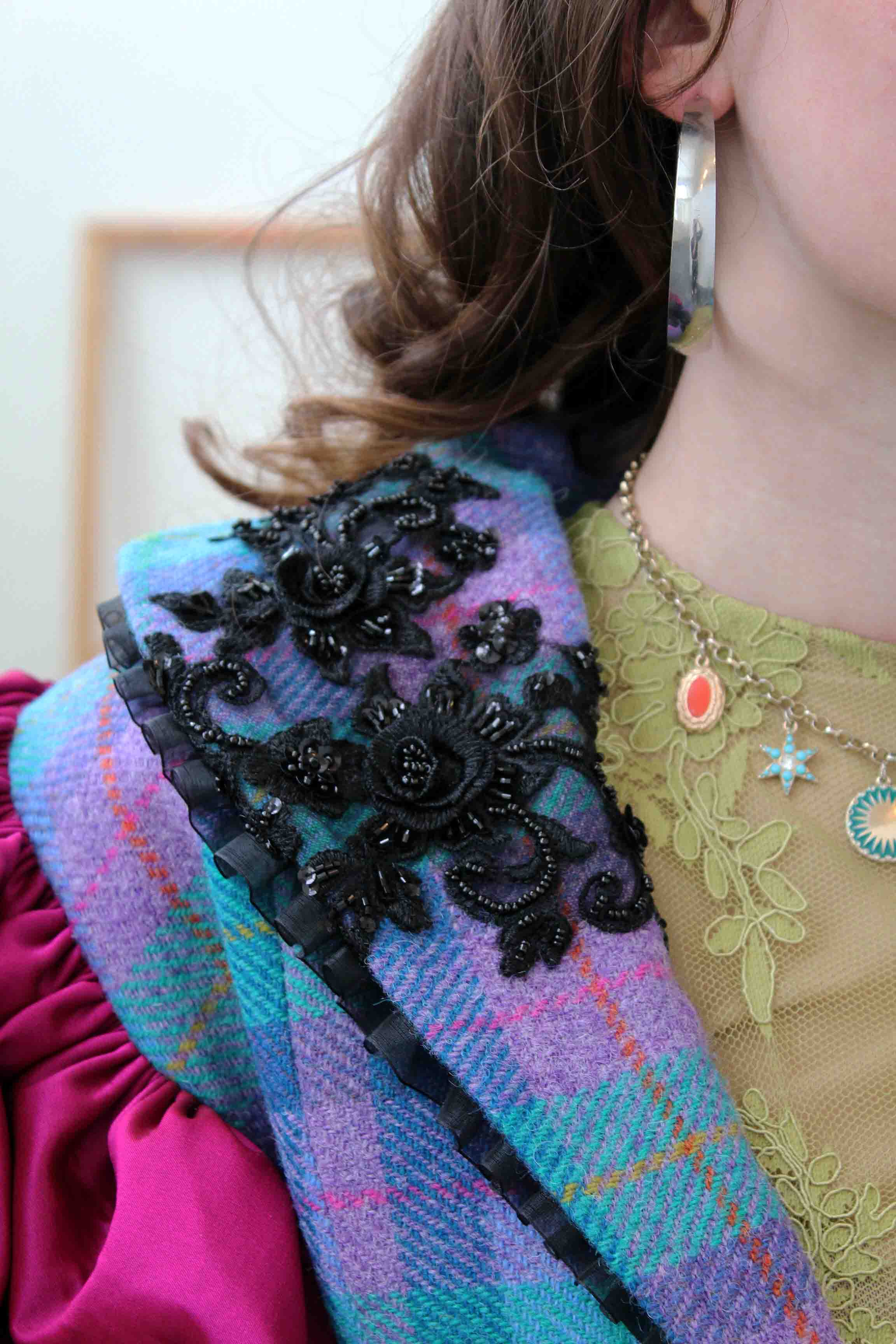 a closeup of a waistcoat made of checked wool tweed in purple and blue, with a bejeweled floral applique on the left hand side of the collar 