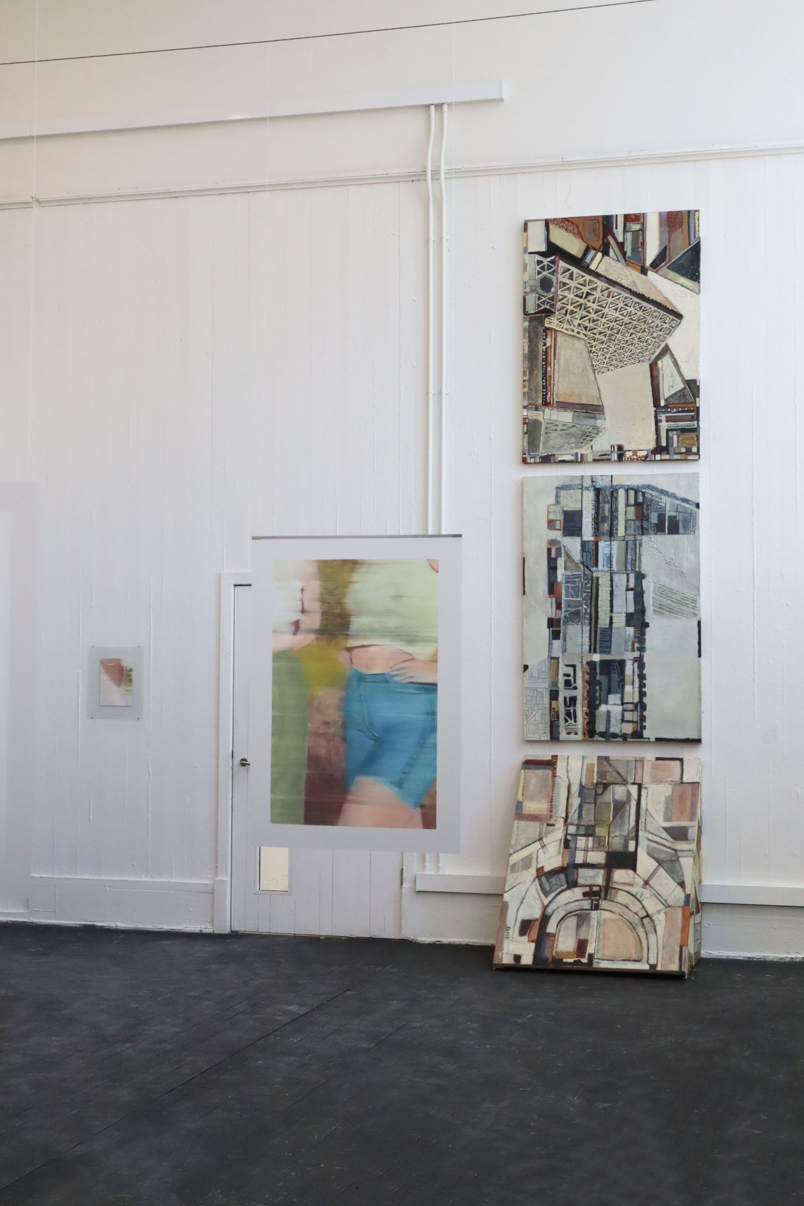 Installation shot of a painting hanging from wires in the centre of the room
