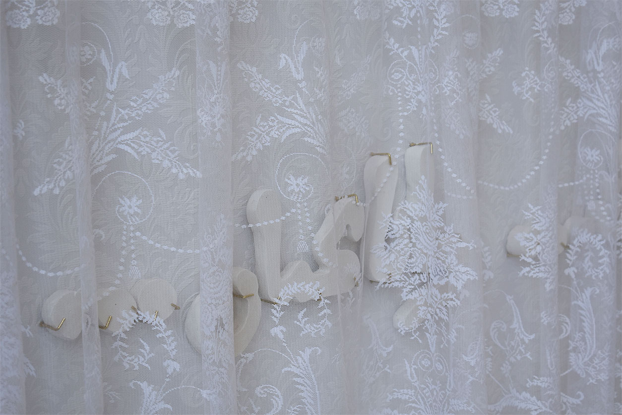 arabic plaster letters mounted behind lace curtain