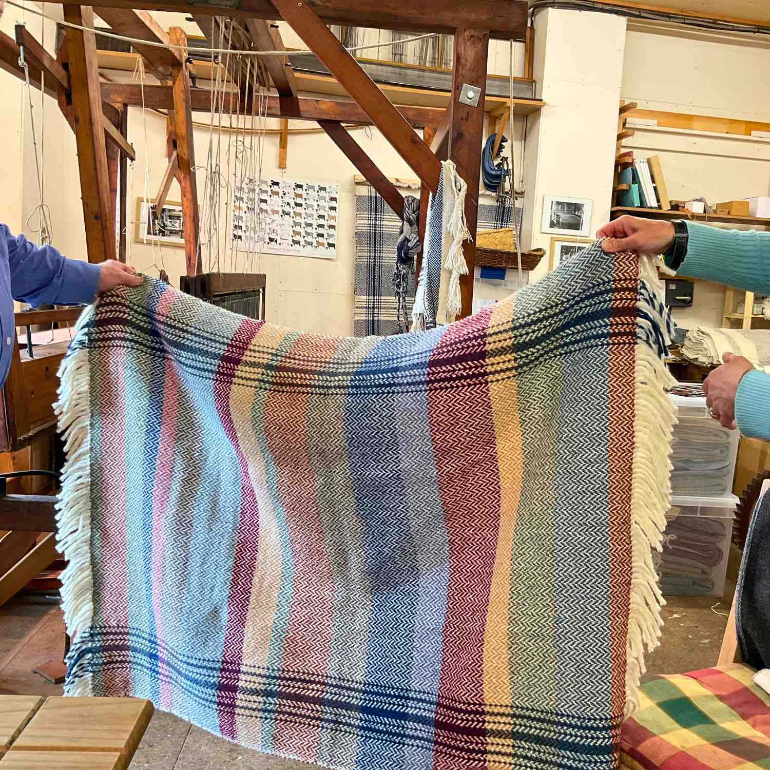 weavers displaying a community piece developed at their studio