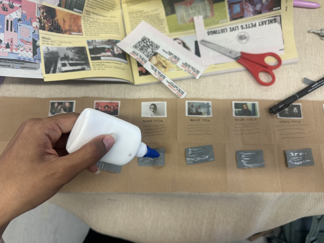 Top view of a hand building a paper prototype with magazines, paper and glue