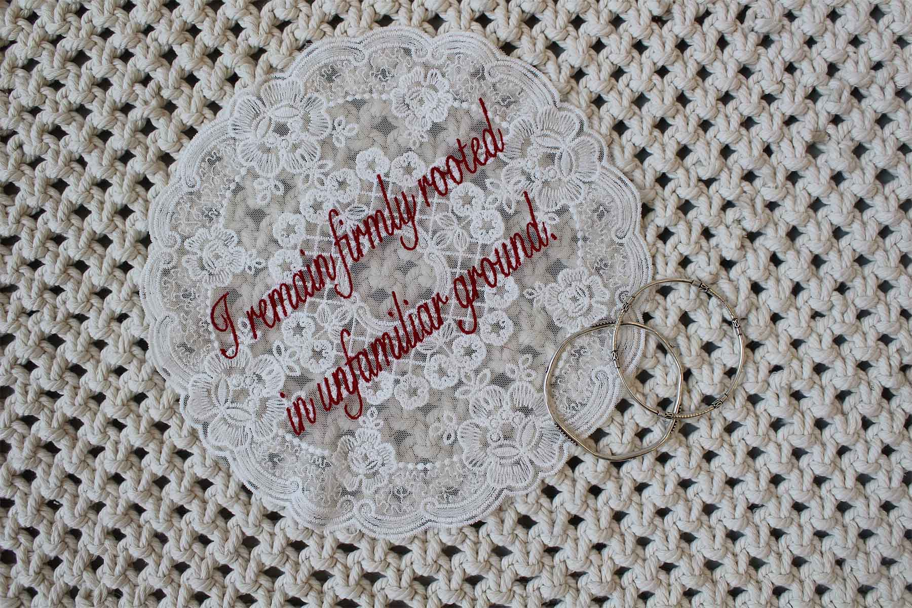 embroidered lace doily reading 'I remain firmly rooted in unfamiliar ground'